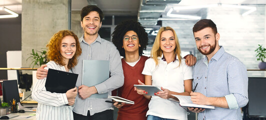 Wall Mural - Successful company with happy workers. Cheerful multiethnic team posing at camera, panorama