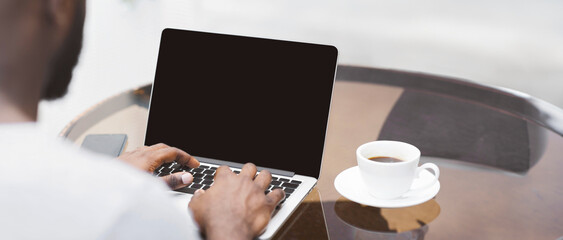 Poster - A close-up view of a mans hands typing on a laptop with a cup of coffee in the background.