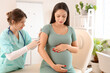 © Pixel-Shot - Young pregnant woman receiving vaccine in clinic