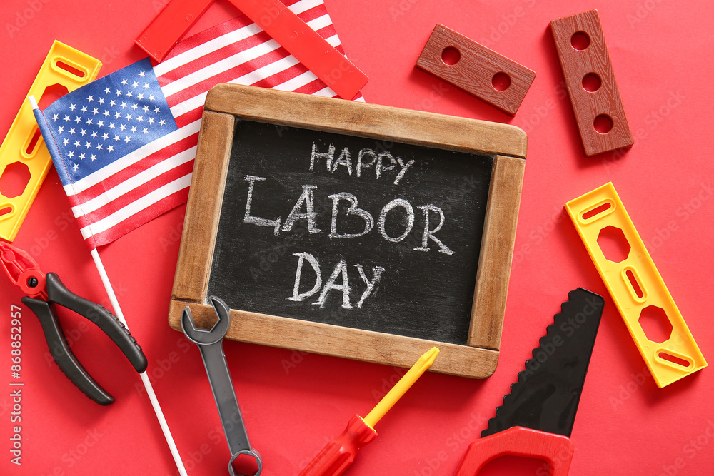 Chalkboard with text HAPPY LABOR DAY, USA flag and toy tools on red background. Labor Day celebration