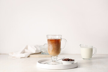 Wall Mural - Glass cup of iced latte, bowl with coffee beans and jug of milk on white background