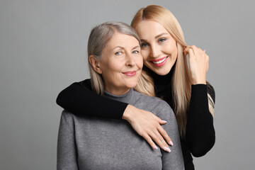 Sticker - Family portrait of young woman and her mother on grey background