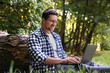 © New Africa - Smiling freelancer working with laptop on green grass in forest. Remote job