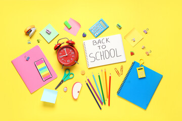 Wall Mural - Alarm clock, notebook with text BACK TO SCHOOL and different stationery on yellow background