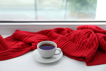 Wall Mural - Red knitted scarf, hat, tea on windowsill