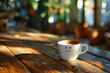 © Kuo - A photo of a coffee cup with a sad face on a wooden table, with a blurry background and sunlight.