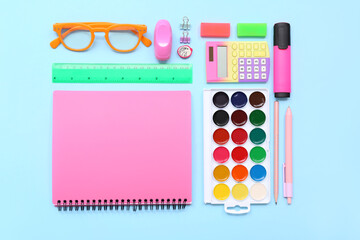 Wall Mural - School supplies with notebook, palette and eyeglasses on blue background. Top view