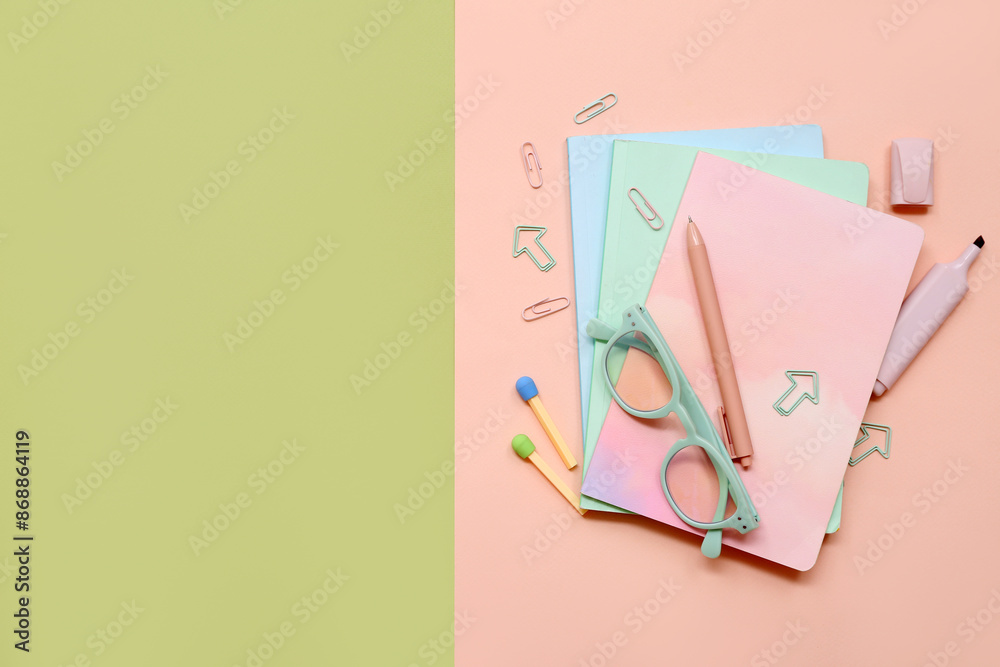 School supplies with eyeglasses and notebooks on colorful background. Top view