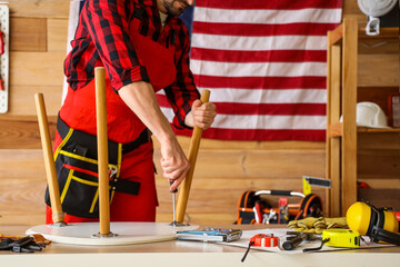 Poster - Male worker repairing table in workshop. Labour Day celebration