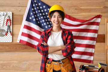 Wall Mural - Female Asian worker against USA flag in workshop. Labour Day celebration