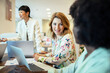 © Marko Geber - Multiethnic female colleagues discussing work with laptops in a modern office
