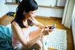 © Marko Geber - Smiling Asian woman using smartphone at home