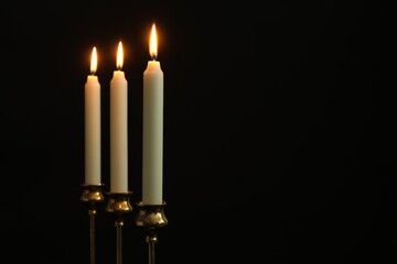 Wall Mural - Burning candles on black background. Space for text