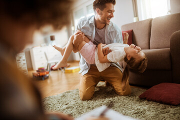 Wall Mural - Father playing with daughter in living room at home