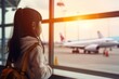 © Baba Images - Portrait of a little Asian girl looking out of airport terminal window