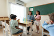 © Kawee - Adorable student learn with teacher in classroom at elementary school.