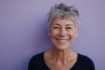 Wall Mural - Portrait of a smiling senior woman with grey hair against purple background