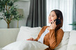 © Monster Ztudio - Happy young asian woman relax on comfortable couch at home texting messaging on smartphone, smiling girl use cellphone chatting