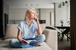 © anatoliy_gleb - Young woman thoughtfully looking away. Beautiful female relaxing on couch and reading. Woman in casual clothes sitting on cream sofa and thinking.