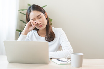 Tired asian young woman burnout, stressed from problem work at desk in office, looking at laptop computer, feeling sick, pain eye strain rubbing dry irritated eyes fatigued working late on deadline.