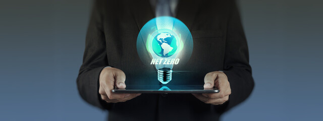 A businessman in a suit holds a tablet with a glowing light bulb icon featuring the Earth and the words 