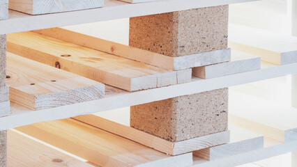 Poster - A stack of wooden pallets with a brick base. The pallets are stacked on top of each other, creating a sturdy base. Concept of strength and durability