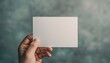 © narak0rn - Hand holding a blank white card against a textured green background, perfect for mockups, presentations, and design templates.