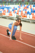 © yavdat - woman, dressed in blue athletic gear, assumes a starting stance on a track, showcasing her readiness for a run. proper positioning and mental preparation in fitness routines.