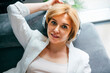 © Westend61 - Smiling businesswoman wearing wireless headphones and relaxing on sofa at home