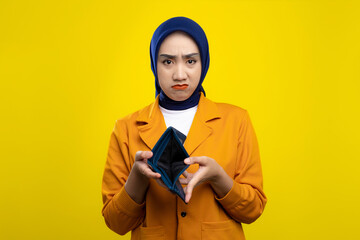Wall Mural - Sad young Asian woman showing empty wallet at camera isolated on yellow background