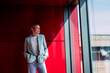 © Westend61 - Happy businesswoman with hands in pockets looking out through window at office