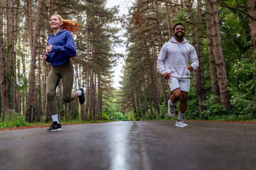 Wall Mural - An energetic duo enjoying a morning run in the forest. Laughing and jogging together, they showcase the fun and motivation of outdoor fitness activities.