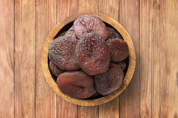 Wall Mural - chocolate dried apricots in bowl on wooden table background, top view. organic vegetarian food.