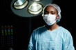 © Seventyfour - Waist up portrait of African American young woman as female surgeon looking at camera standing in operating room and wearing mask, copy space
