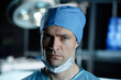 © Seventyfour - Close up portrait of tired male surgeon looking at camera standing in operating room with low light