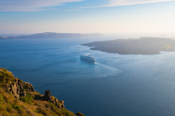 Wall Mural - Santorini island, Greece. Cruise ship near the coast at sunset. Blue sea and the blue sky.