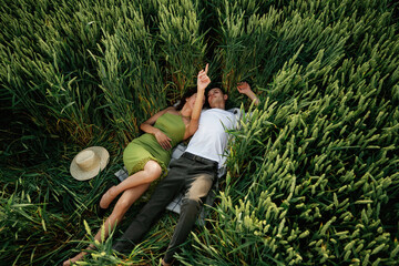 Wall Mural - Couple is lying down on the agricultural field with high wheat that is growing