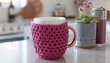 © Naveed - Modern crochet magenta coffee cozy with sleek designs, wrapped around a stylish mug in a minimalist kitchen