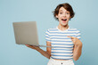 © ViDi Studio - Young happy IT woman wears striped t-shirt casual clothes hold use work point index finger on laptop pc computer isolated on plain pastel light blue cyan background studio portrait. Lifestyle concept.
