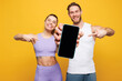 © ViDi Studio - Young strong fitness trainer sporty two man woman wear blue clothes spend time in home gym hold use show blank screen mobile cell phone isolated on plain yellow background. Workout sport fit concept.