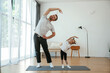 © standret - Spine exercise. Father with little daughter are doing yoga at home