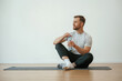 © standret - Taking a break, with bottle of water. Yoga man is sitting on a mat at home