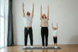 © standret - Warm up exercises. Family of mother, father and daughter are doing yoga at home