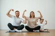 © standret - Showing the biceps, strong. Family of mother, father and daughter are doing yoga at home