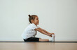 © standret - Side view, stretching. Cute little girl is sitting on the yoga mat and doing exercises