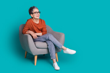 Sticker - Full length photo of lovely pensioner lady sit armchair look empty space dressed stylish brown garment isolated on cyan color background