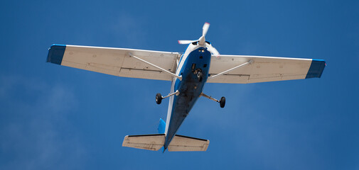Light private airplane for recreational use in flight,
small retro airplane, clear blue sky in background