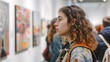 © naphat - A young woman visits a charity art exhibition where people come to view and buy artwork to support good causes. which was held on International Charity Day.