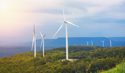 Wall Mural - three wind turbines are on a hillside, with the sun shining through the clouds