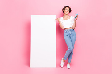 Wall Mural - Full length photo of adorable funny girl dressed white top reading modern device thumb empty space isolated pink color background